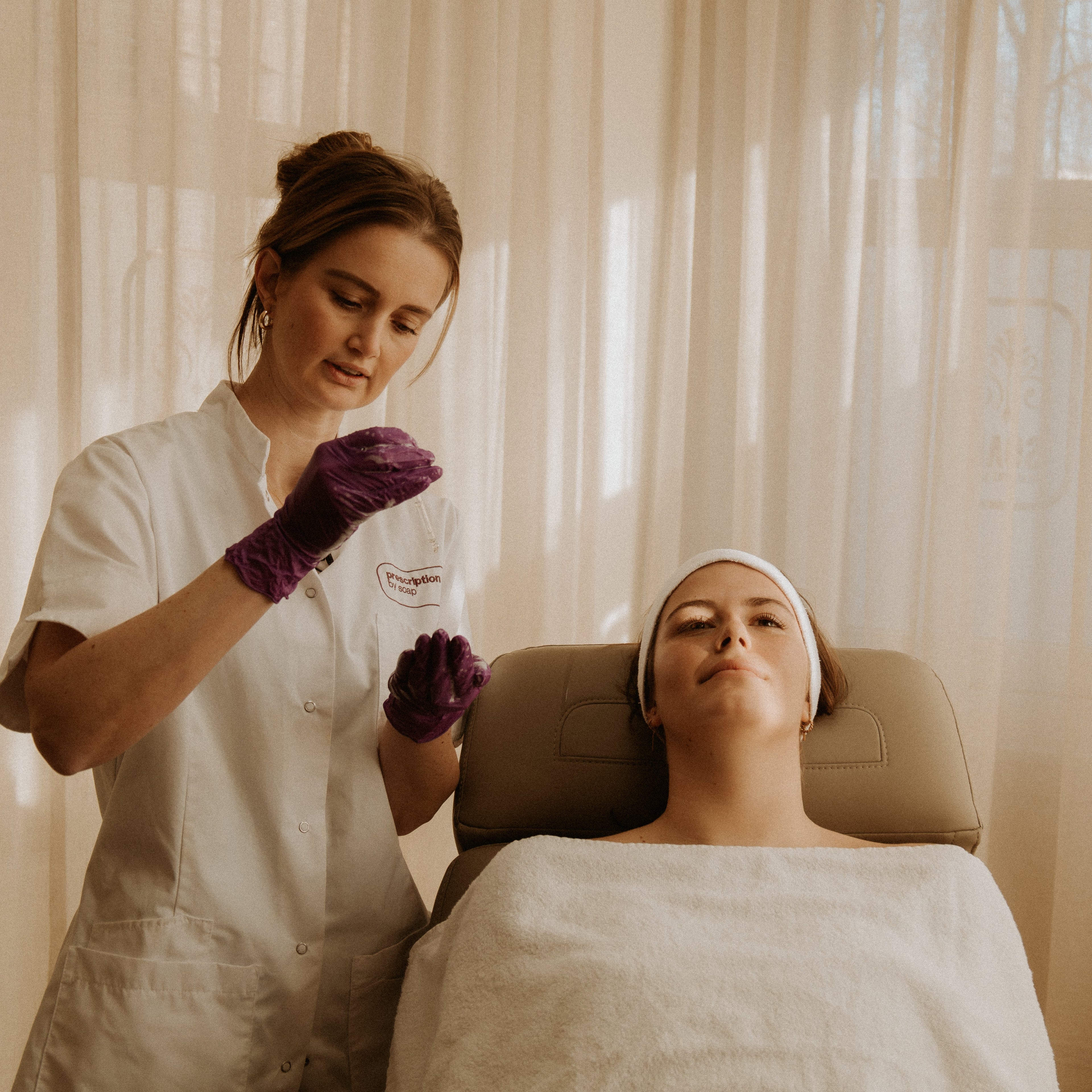 Er vindt een gezichtsbehandeling plaats waarbij de skin expert een serum aan brengt bij de klant