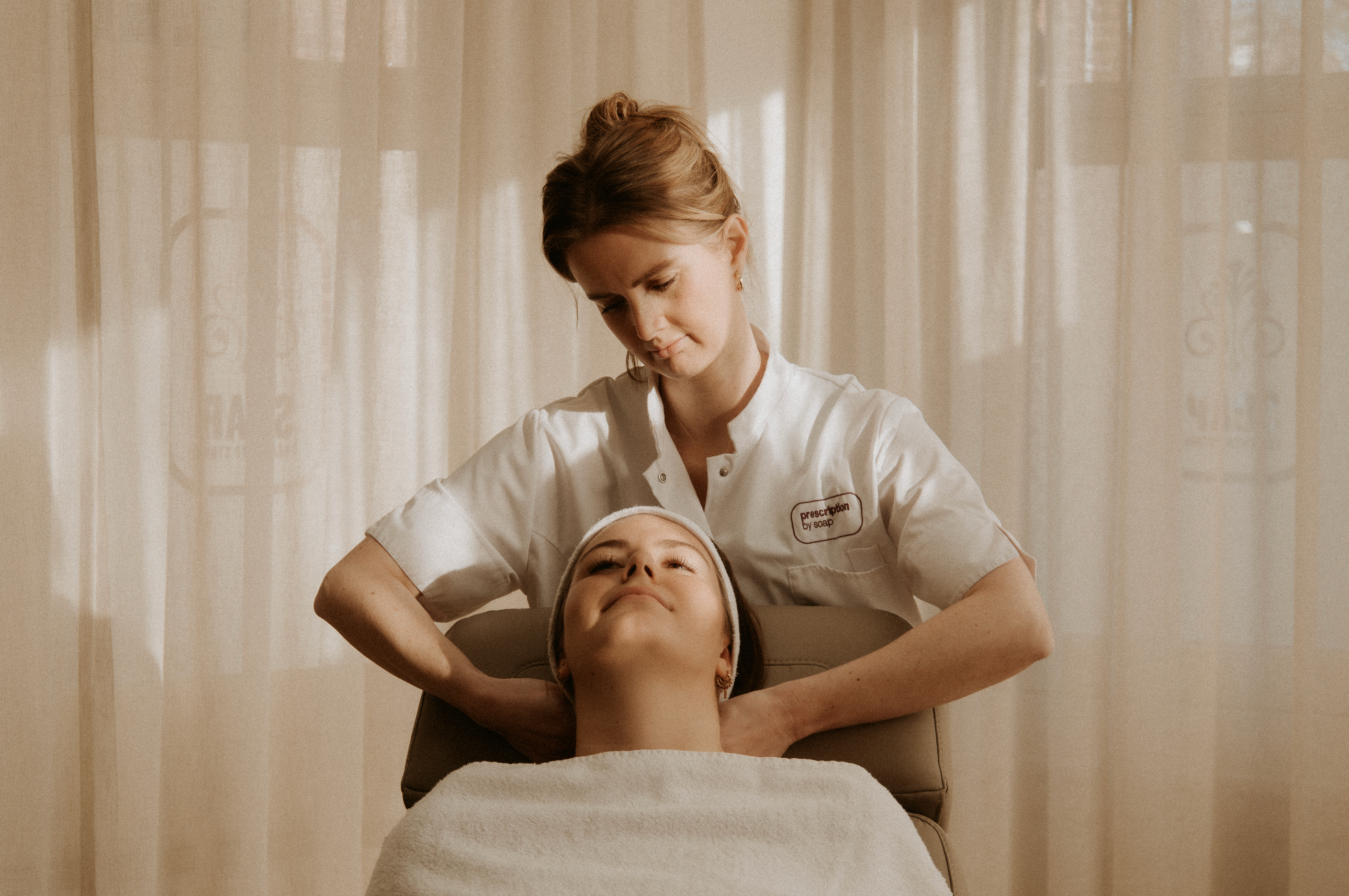 Huidexpert behandelt cliënte met Prescription Skincare en brengt het aan in haar nek terwijl ze op de stoel ligt