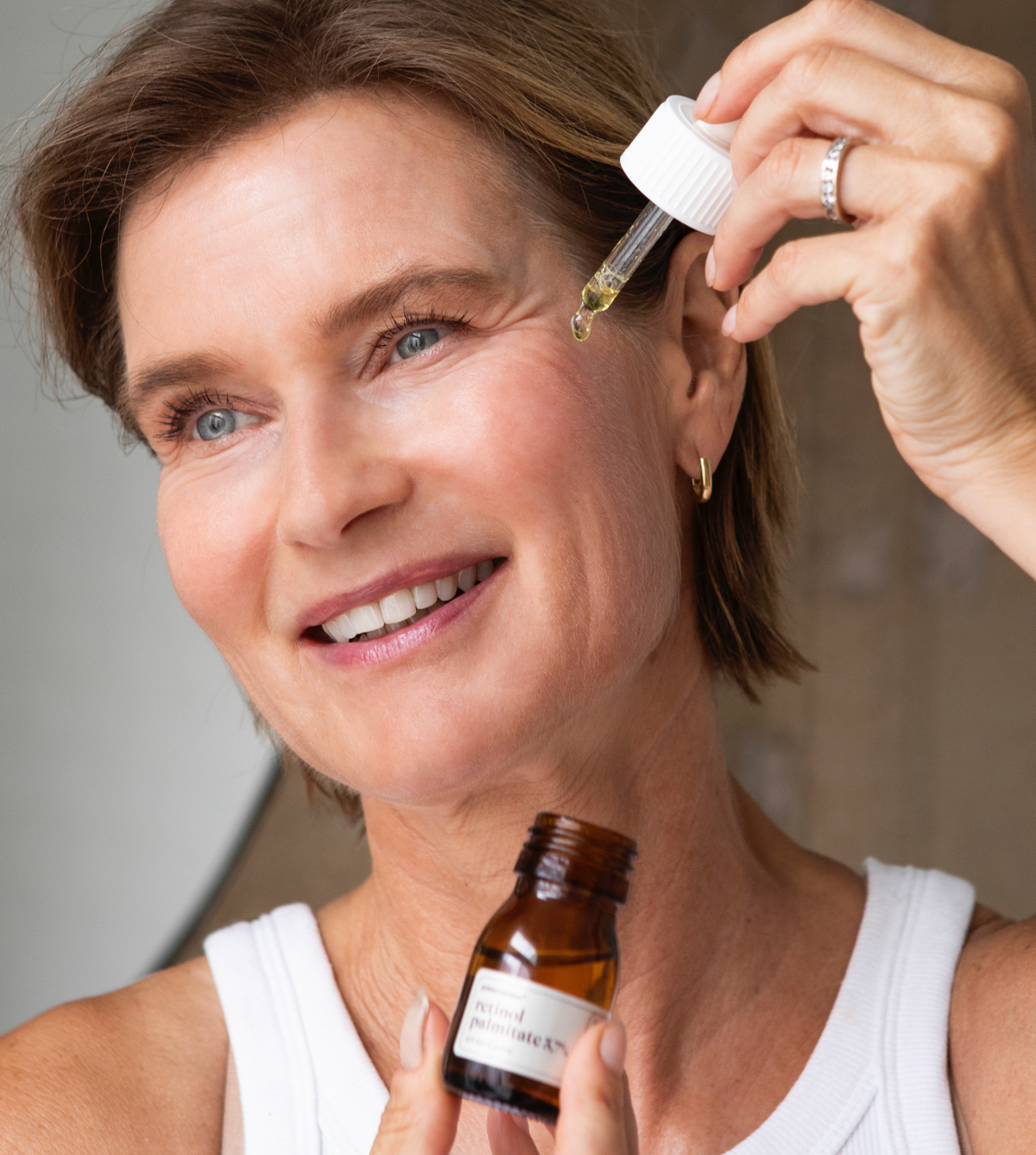 Een vrouw brengt retinol serum aan op haar gezicht 